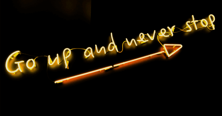 Gul neon tekst Go up and never stop på sort bakgrunn