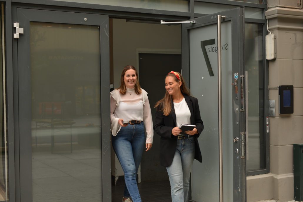 to smilende jenter på vei ut fra kontoret