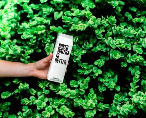 Person som holder en kartong med teksten "Boxed water is better"